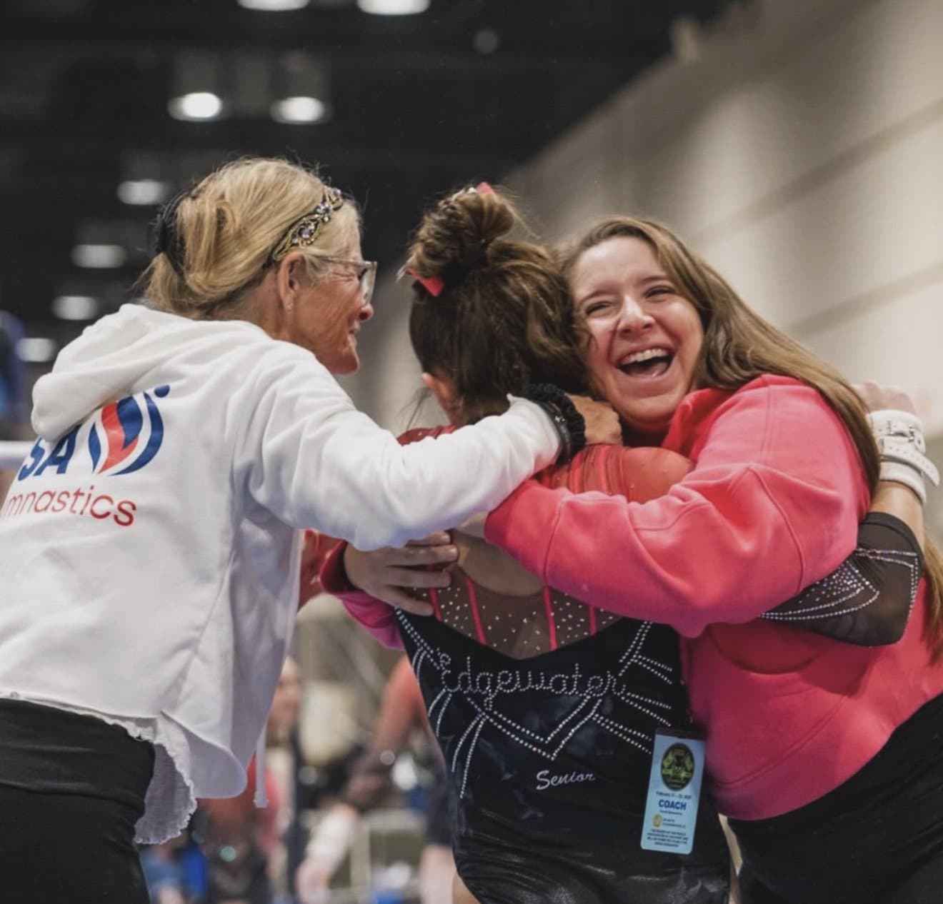 Edgewater coaches celebrating with a team gymnast at a meet